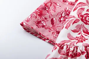 Close-up of red and pink floral pattern fabric with quality stitching on women's dress.
