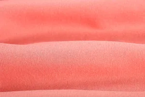 Macro detail view showing soft coral pink knitted fabric texture for women jumpsuit