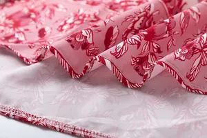 Close-up detail of the pink floral print fabric and fine hemline stitching on a summer dress.