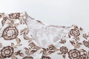 Detailed view of V-neckline and brown floral patterns on white summer maxi dress