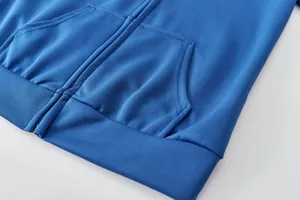 Détail d'un sweat à capuche bleu avec fermeture éclair, poches et bord-côte texturé