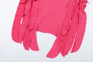 Detail of a vibrant hot pink bodycon dress with irregular ruffle trim and long ribbons.