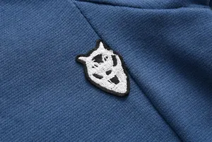 Detail shot of a black and white animal head embroidery patch on a blue long sleeve hoodie