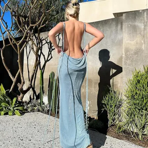 Back view of a blue backless halter maxi dress featuring long strap details in sunlight