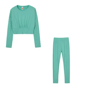 Flat lay view of a mint green women's long-sleeve crop top and leggings sports set.