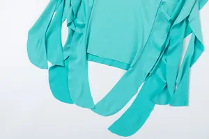 Close-up of turquoise irregular hemline with flowing fabric strips on a summer dress