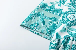 Close-up detail of teal floral print and ruffled sleeve on a white summer dress.