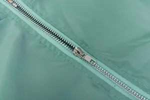 Gros plan sur la fermeture éclair en métal argenté d'un vêtement de sport vert menthe.