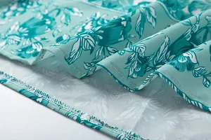 Close-up detail of the fine stitching and floral print on a lightweight teal summer dress hem.
