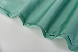 Vue rapprochée de la texture du tissu côtelé vert menthe sur l'ourlet d'un survêtement.