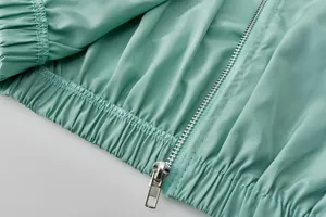Gros plan d'une veste de sport bleu sarcelle avec fermeture éclair et ourlet élastique.