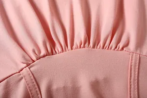 Detailed view of ruched waistband and fine stitching on a pink athletic outfit