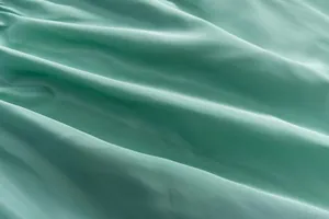 Gros plan détaillé du tissu vert menthe montrant la texture douce et les plis naturels.