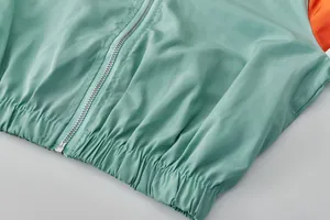 Détail macro d'une veste de sport vert menthe légère avec fermeture éclair et ourlet.