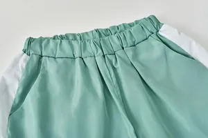Gros plan de la taille élastique d'un short de sport bicolore vert menthe et blanc.