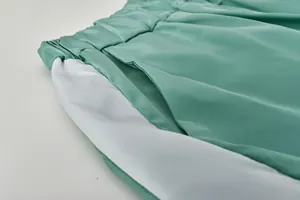 Détail de la taille élastique et de la poche latérale sur un pantalon vert et blanc