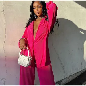 Full-body shot of fuchsia pleated two-piece outfit featuring shirt and trousers