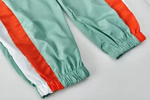 Détail des chevilles élastiquées sur un pantalon de sport tricolore vert et orange