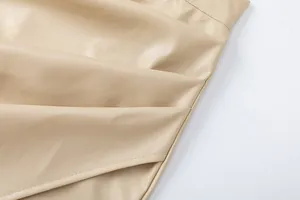 Close-up detail of beige PU leather skirt showing elegant draped texture and fine stitching.
