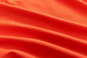 Macro view of bright orange sports fabric texture with soft natural folds and shadows