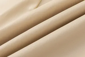 Close-up macro detail of high-quality beige PU leather fabric with fine grain texture