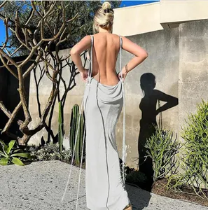 Back view of a white backless maxi dress with halter ties in a sunny outdoor setting.