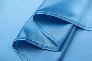 Λεπτομερής μακροεντολή της ραφής και της λείας υφής σε μια γαλάζια σατέν φούστα.