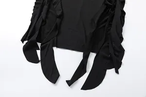 Detailed macro shot showcasing the irregular ruffled hem design of a black bodycon dress