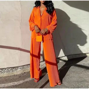 Vibrant orange pleated two-piece set with long-sleeve shirt and wide-leg pants