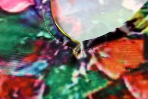 Close-up view of the fine stitching and vibrant floral print on a V-neck dress neckline.