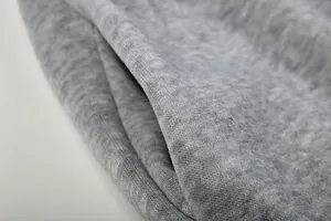 Detailopname van de grijze gemêleerde stof en de zijzak van een casual hoodie.