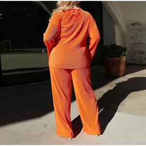Rear view of bright orange pleated two-piece casual set featuring wide-leg pants
