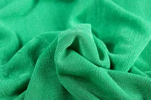 Macro view of vibrant green knitted fabric texture showing fine weave details .