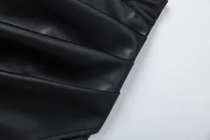 Close-up detail of black PU leather skirt featuring elegant ruched pleats and texture