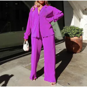 Detail view of purple pleated loose shirt and wide-leg trousers set in urban setting