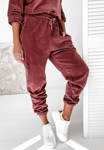 Dettaglio ravvicinato della tuta in velluto bordeaux con pantaloni jogger e scarpe