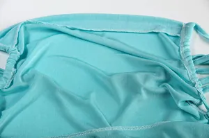 Close-up of turquoise ribbed fabric and stitching on a stylish backless halter dress