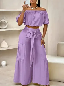 Ensemble chic violet deux pièces avec haut à épaules dénudées et pantalon taille haute à nœud.
