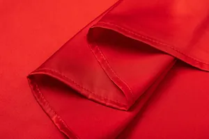 Κοντινό πλάνο κόκκινου σατέν υφάσματος που δείχνει λεπτές ραφές και λεία υφή