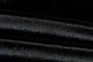 Nahaufnahme von hochwertigem, glänzendem Samtstoff mit dezenten bunten Glitzerfasern.