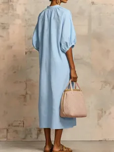 Back view of a loose-fitting light blue cotton linen midi dress with elegant puff sleeves
