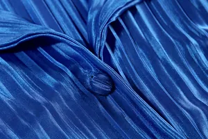 Close-up of royal blue pleated fabric texture and matching fabric-covered button