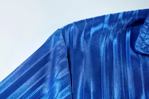 Macro view of vibrant blue pleated fabric and shoulder seam detail on a casual suit.