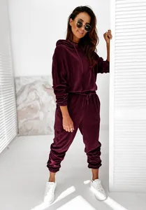 Dettaglio di una tuta in velluto bordeaux con felpa con cappuccio e pantaloni sportivi.