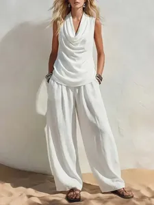 Close-up of elegant white two-piece set featuring draped sleeveless top and wide-leg pants