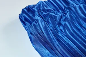 Close-up of vibrant blue pleated fabric with silky sheen and fine texture