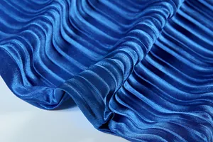 Close-up of vibrant blue pleated fabric showing elegant satiny sheen and texture
