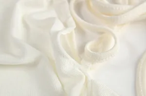 Macro detail of white ribbed fabric and thin spaghetti straps on a halter dress