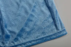 Nahaufnahme der weichen blauen Samttextur und des Saums eines schmalen Schlitzkleids.