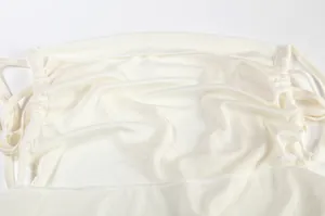 Close-up view of a white halter neck backless dress showing fabric texture and straps